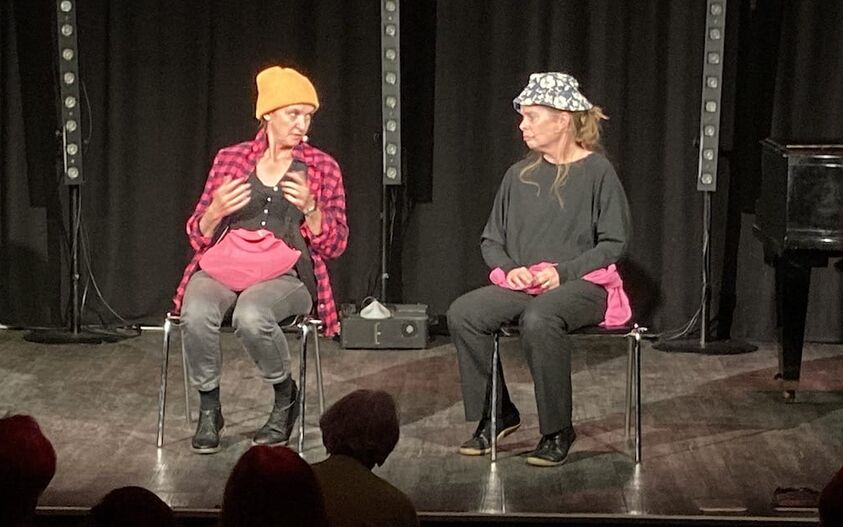 Die „Tabutanten“ Christine G. Holzer und Simone Schmitt sitzen auf der Bühne und schauen sich gegenseitig an.