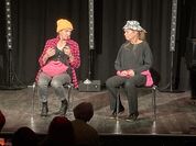 Die „Tabutanten“ Christine G. Holzer und Simone Schmitt sitzen auf der Bühne und schauen sich gegenseitig an.